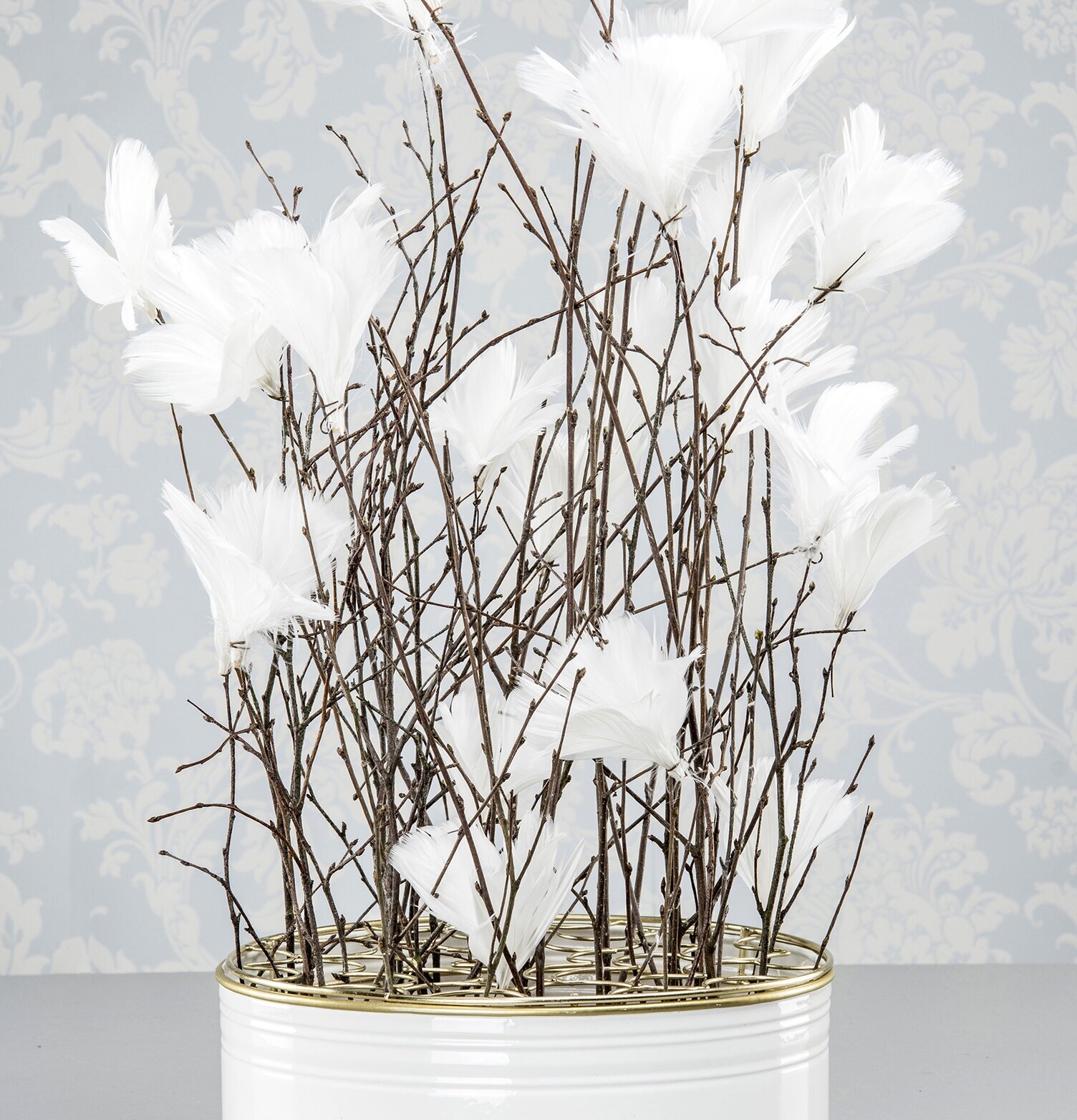 Bild av elegant rund vas i vit och guld med fjädrar