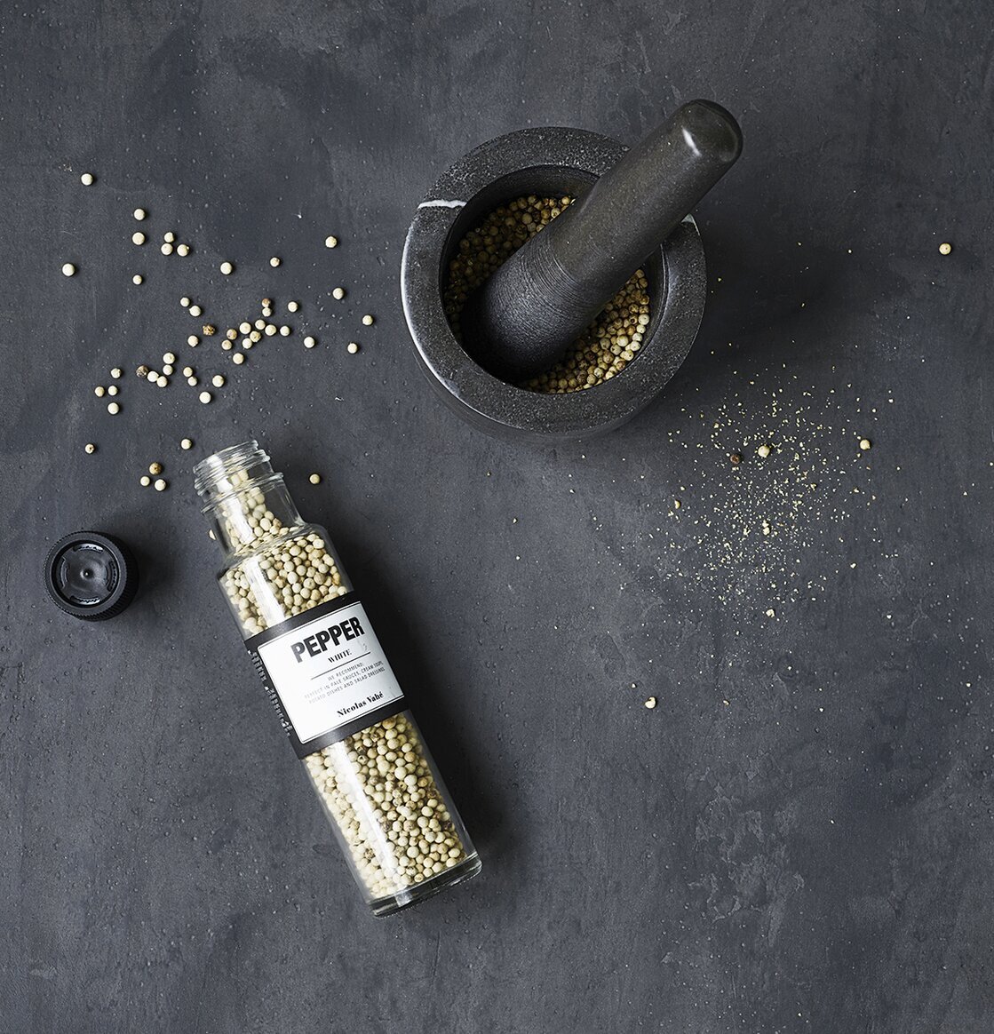 Bild av mortel med vitpepparkorn på mörk yta