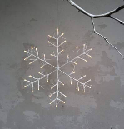 Bild av vit snöflinga med LED-lampor mot cementvägg