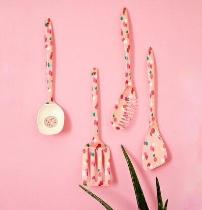 Bild av färgglada köksredskap mot rosa vägg