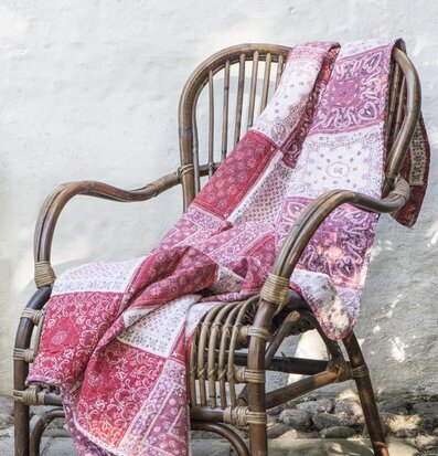 Bild av färgglad pläd på rottingstol i soligt hörn