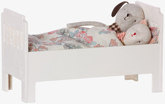 Bild av miniatyrsäng med dockor och blommigt täcke