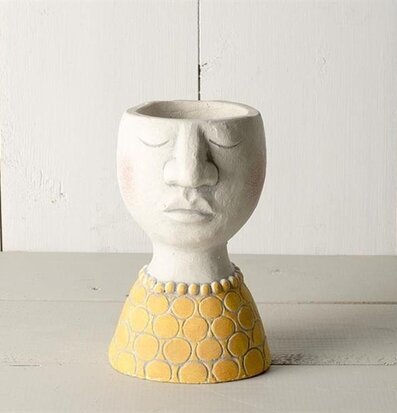 Foto av unik kruka med ansikte och guldfärgad bas