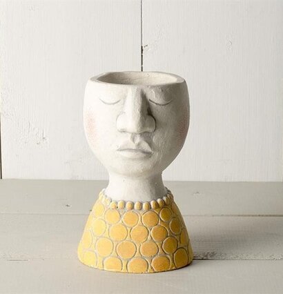 Foto av unik kruka med ansikte och guldfärgad bas