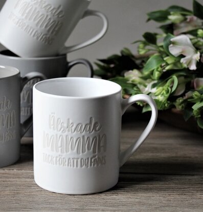 Bild av elegant vit mugg med inskription och växter