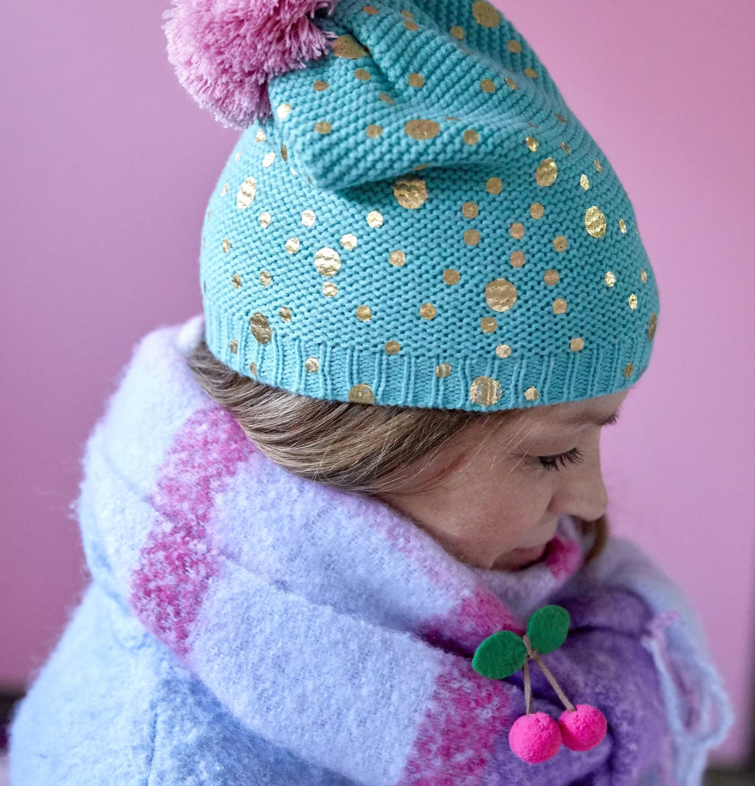 Bild av turkos mössa med guldprickar och rosa tofs