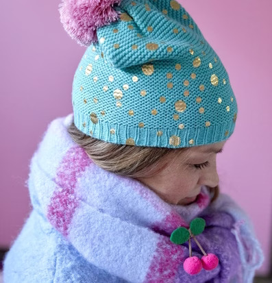Bild av turkos mössa med guldprickar och rosa tofs