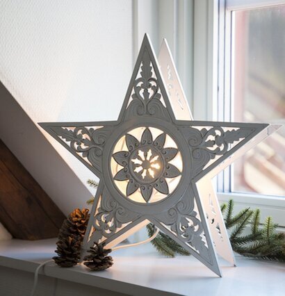 Bild av dekorativ stjärnlampa i trä på fönsterbräda