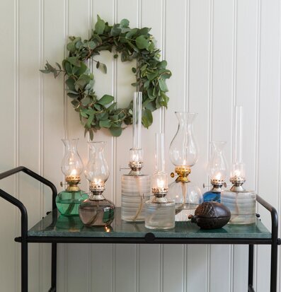 Bild av eleganta fotogenlampor på glasbord med eukalyptus