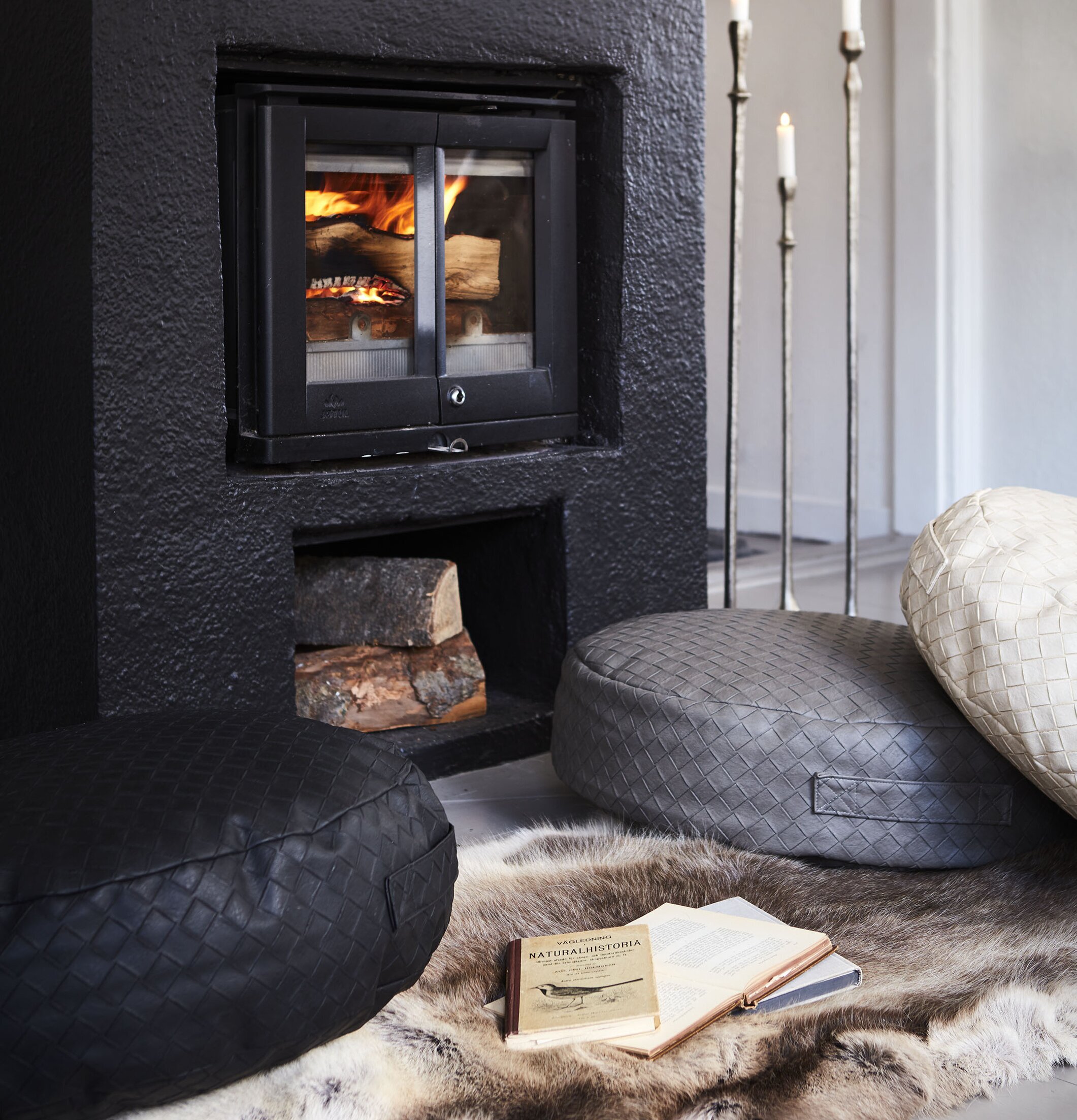 Sittpuff Holly Grå från Affari framför svart öppen spis