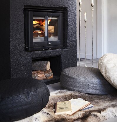 Bild av hemtrevligt rum med eldstad och sittpuffar