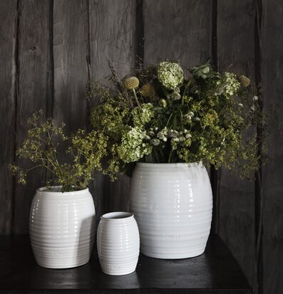 Foto av tre stilrena vita vaser på mörkt träbord