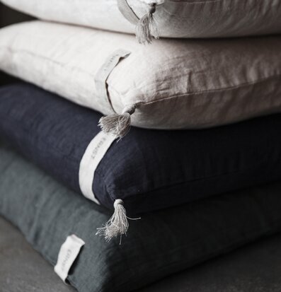 Bild av kuddfodral i linne med tofsar och dova färger