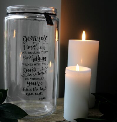 Bild av stilren glaslykta med ljus och gröna blad