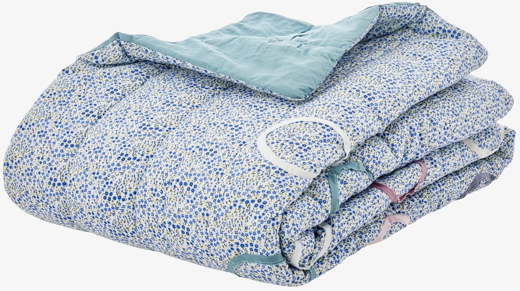 Foto av en filt med blått blommönster och gröna blad