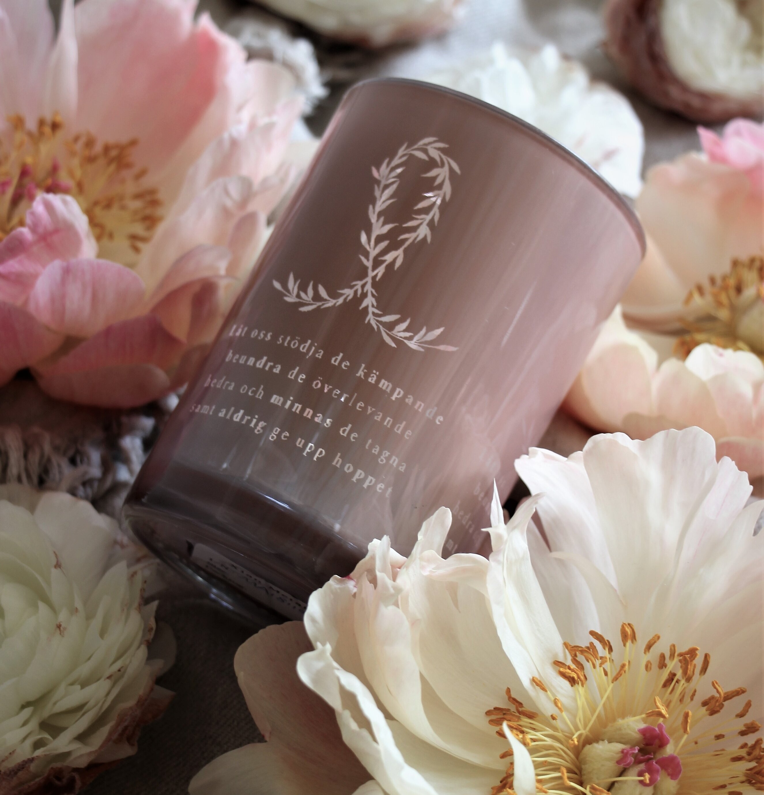 Bild av ljuslykta med rosa bandet och blommor