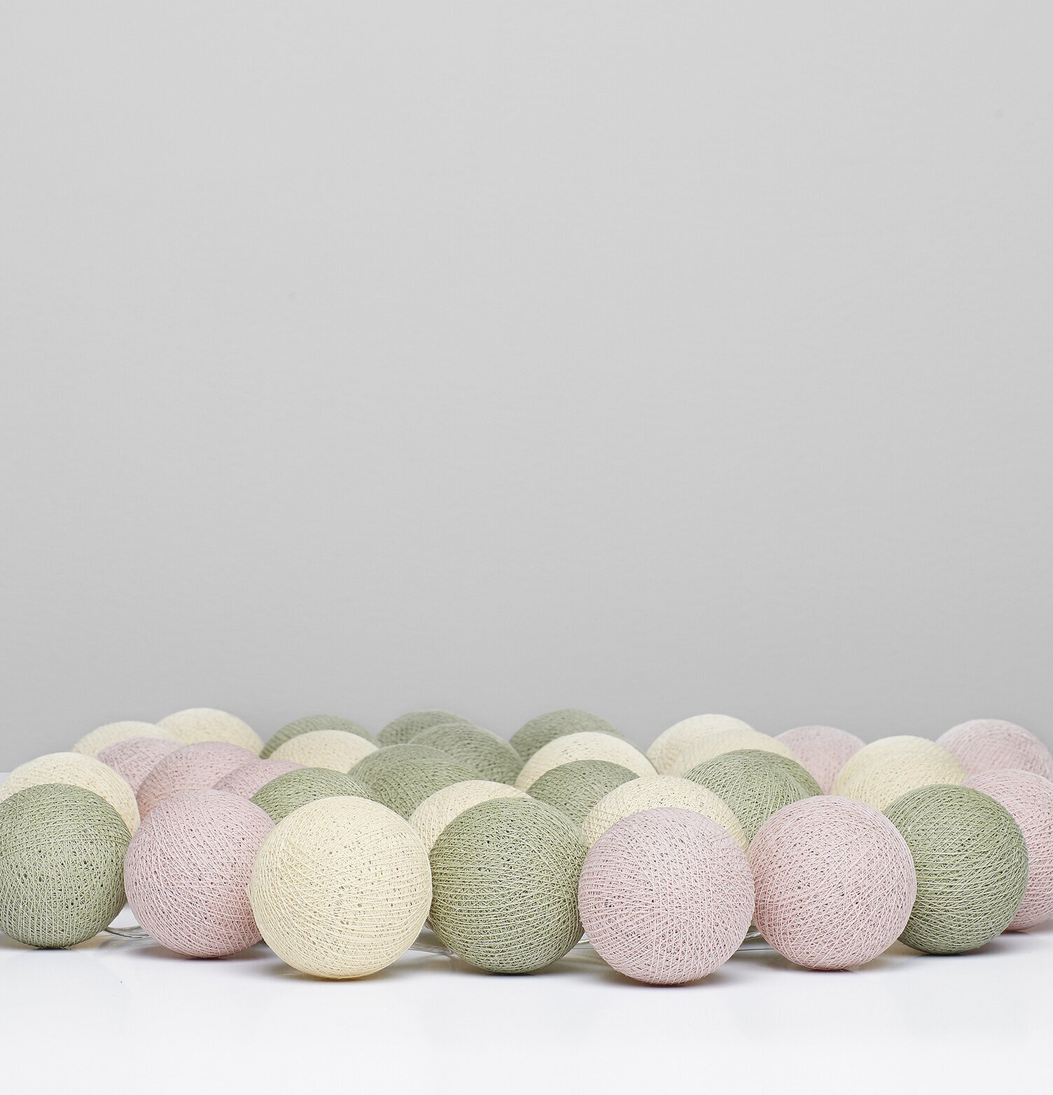 Bild av ljusslinga med bollar i grönt, vitt och rosa