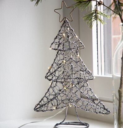 Bild av stilren smidesgran med LED-ljus i fönster