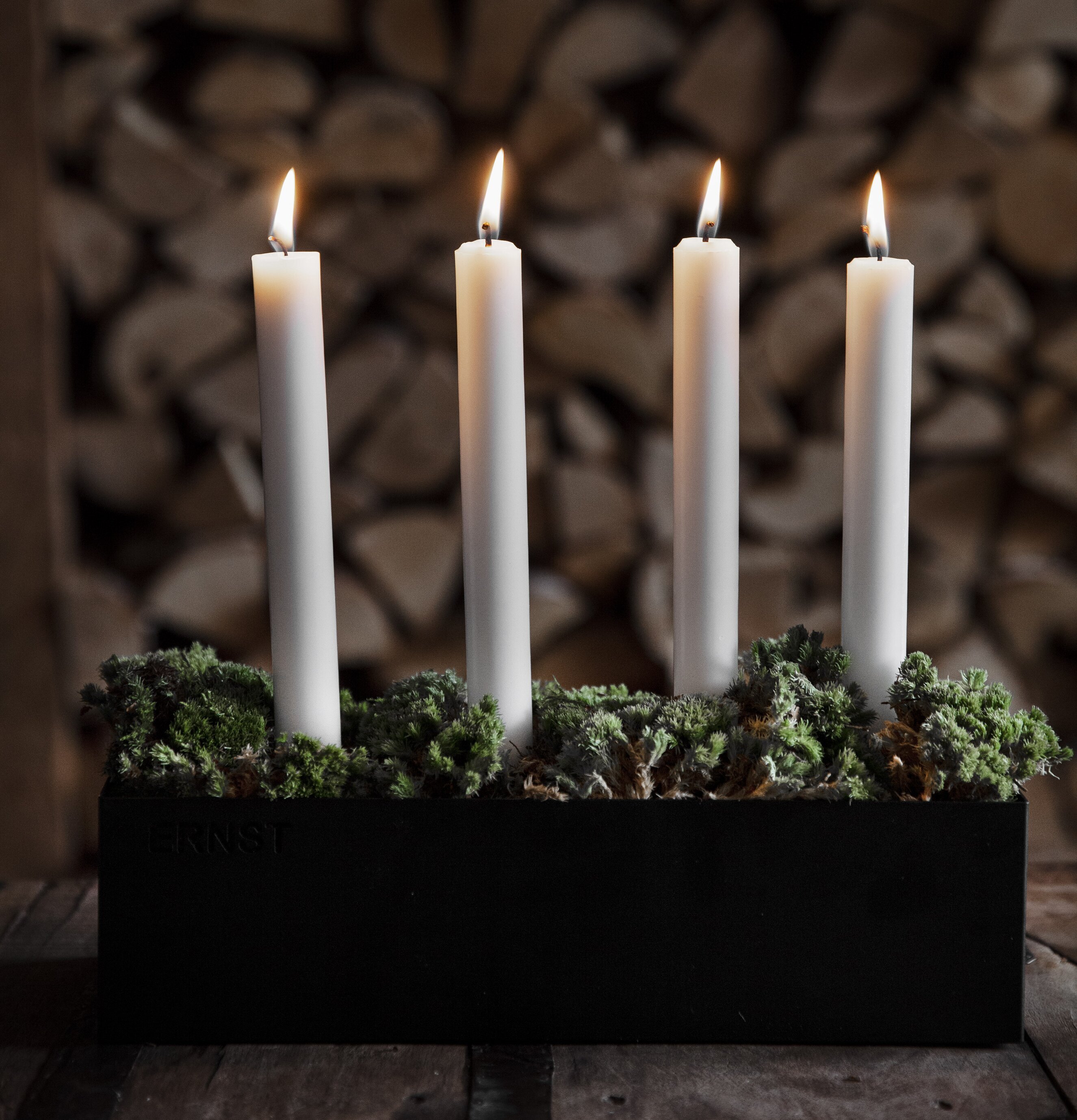 Bild av stilren ljusstake med tända ljus och grönska