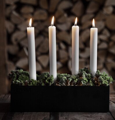 Bild av stilren ljusstake med tända ljus och grönska