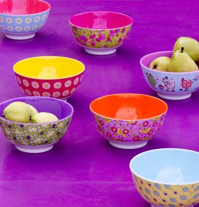 Bild av färgglada melaminskålar på lila bord