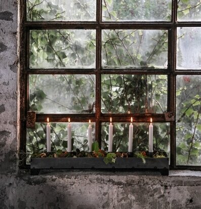 Bild av stämningsfull ljusstake framför gammalt fönster