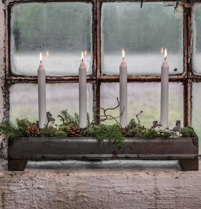 Bild av rustik ljusstake med tända ljus i fönster