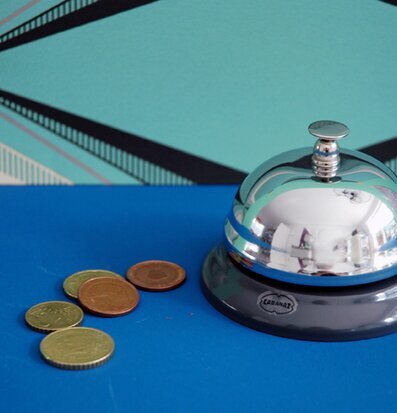 Bild av grå bordsklocka på blå yta med mynt och mönster