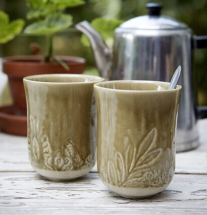 Foto av två dekorativa muggar på rustikt bord