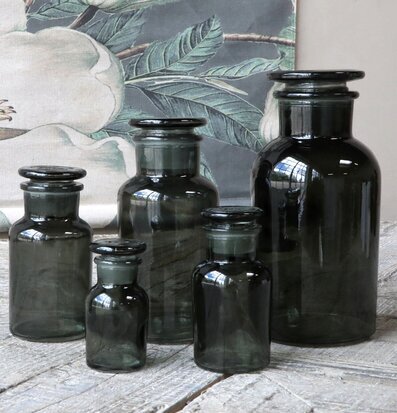 Bild av fem gråa apotekarglas på rustikt träbord