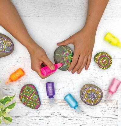 Bild av kreativa händer som målar stenar i neonfärger