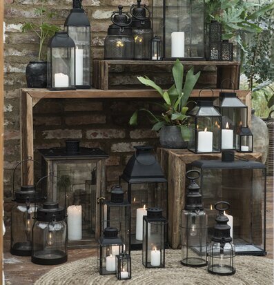 Bild av lyktor och växter mot rustik tegelvägg