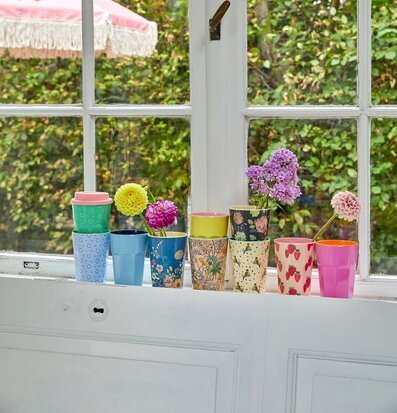 Bild av färgglada muggar på fönsterbräda med blommor