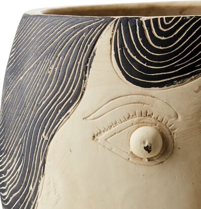 Foto av beige och svart kruka med skulpterat ansikte