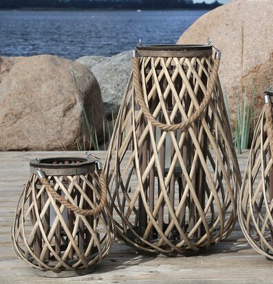 Bild av tre flätade lanterner vid vatten och träplankor
