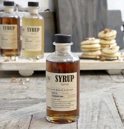 Bild av sirapflaskor och bakverk på rustik träbricka