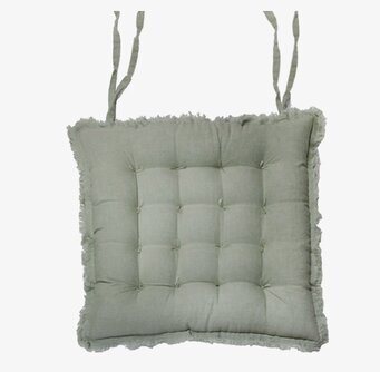 Bild av grön stolsdyna med fransar och rutmönster