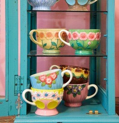 Bild av keramikmuggar i turkost skåp med blommönster
