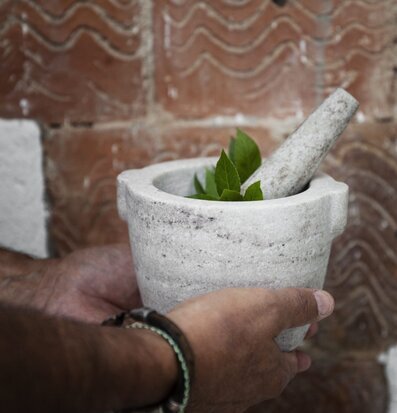 Bild av marmormortel med örter och tegelbakgrund