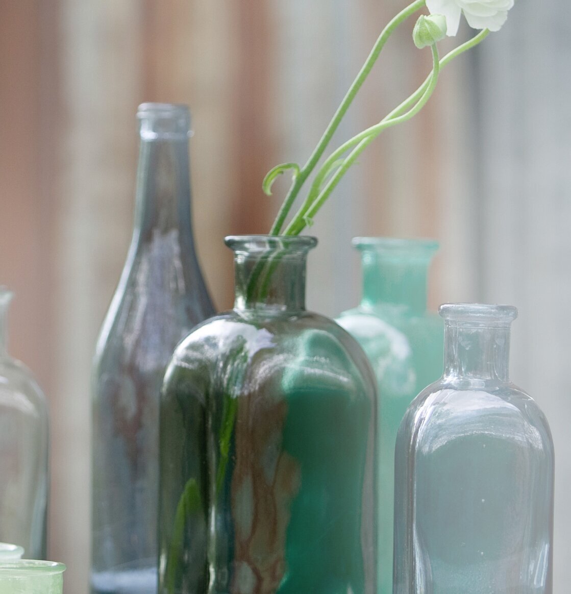 Bordsflaska Rökgrå, 1L från Dixie med vit blomma i vatten