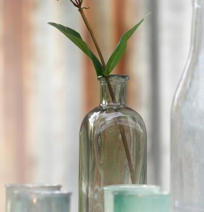 Bild av stilren bordsflaska med ljus och naturinslag