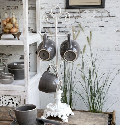 Bild av elegant muggstativ i antikvit på rustikt bord