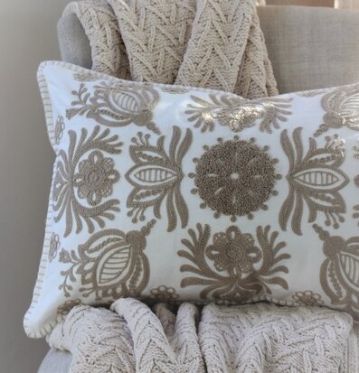 Bild av stilfull kudde med broderi på beige soffa