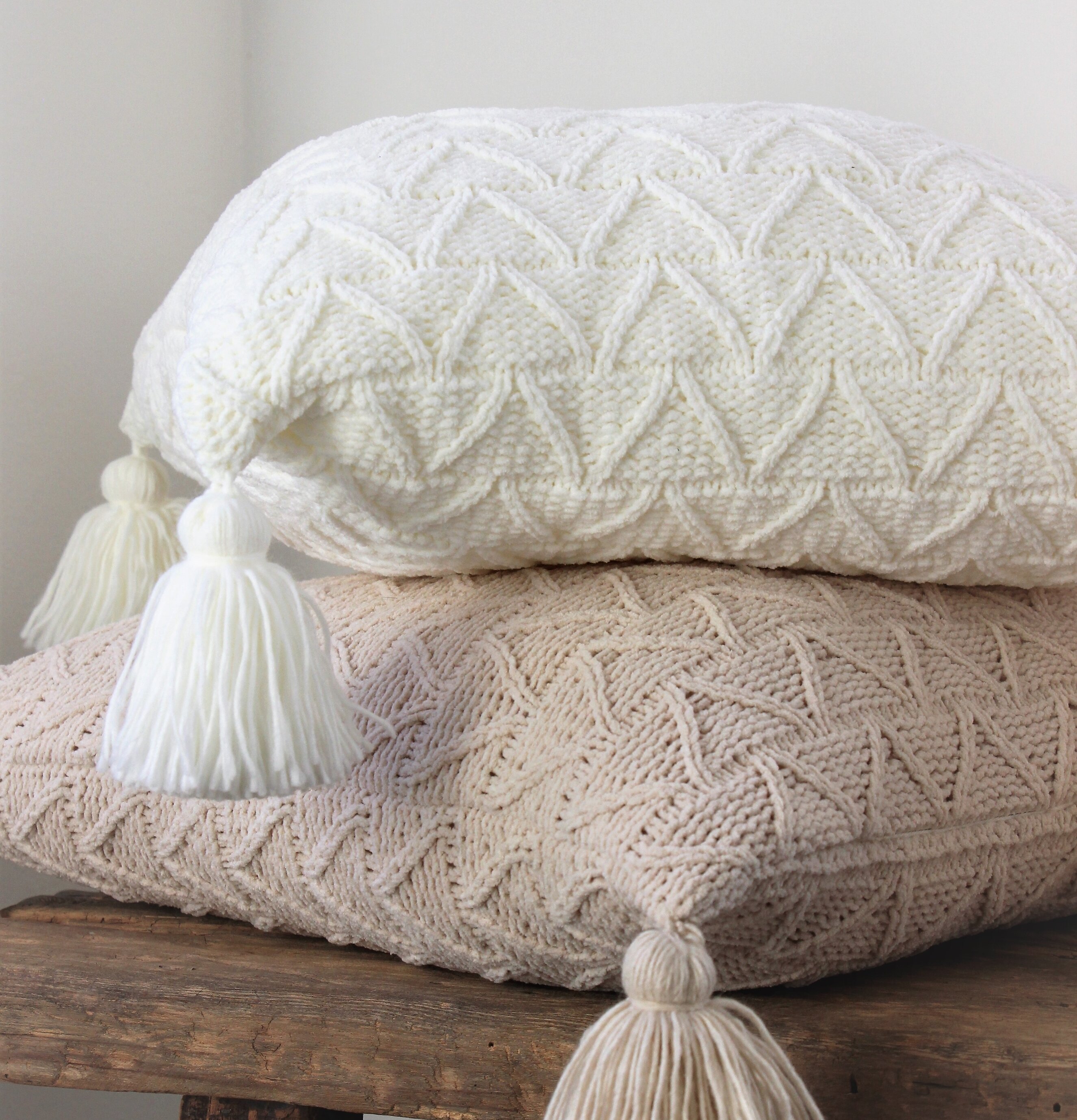 Bild av två kuddar med stickad design och tofsar