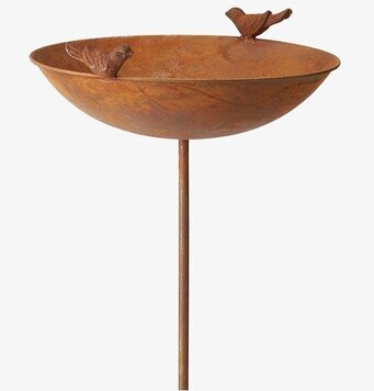 Foto av dekorativt rostfärgat fågelbad i trädgård