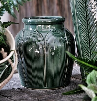 Bild av grön vas med ribbad yta och rustik bakgrund