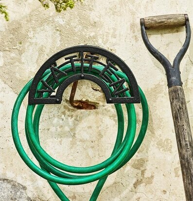 Foto av slanghållare i järn med grön vattenslang