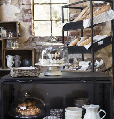 Foto av charmig butiksmiljö med glaskupa och bakverk