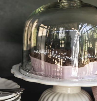 Bild av elegant glaskupa med tårta och keramikfat