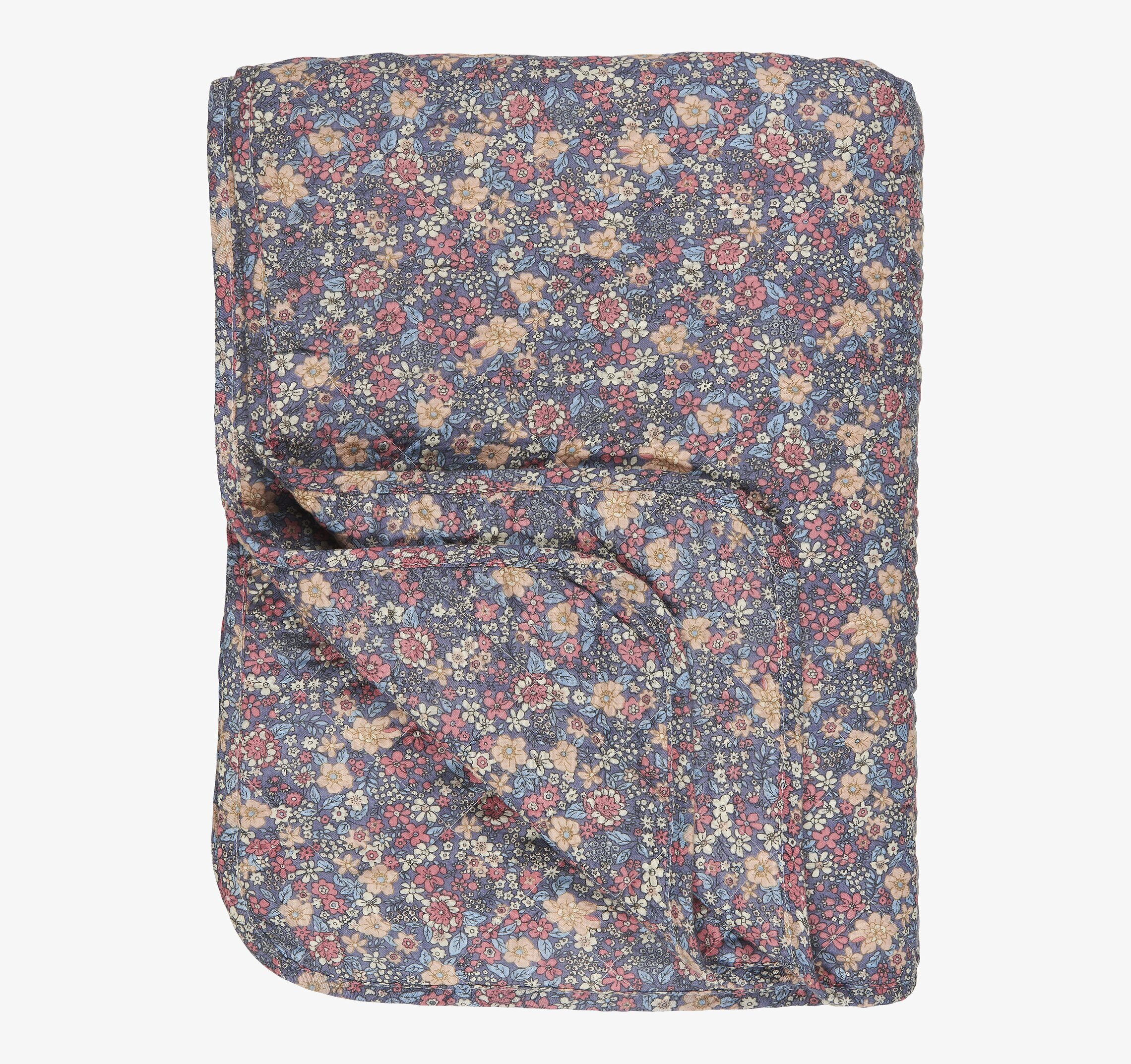 Bild av en quiltad pläd med blommönster och färgklick